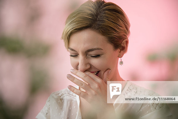 Caucasian woman covering mouth while laughing