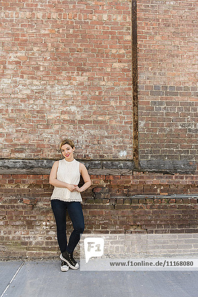 Caucasian woman leaning on brick wall