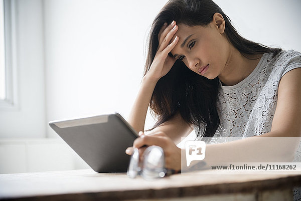 Gemischtrassige Frau mit Kopfschmerzen  die eine digitale Tafel benutzt