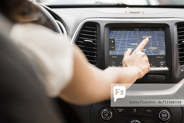 Gemischtrassige Frau  die eine Touchscreen-Navigationskarte im Auto benutzt