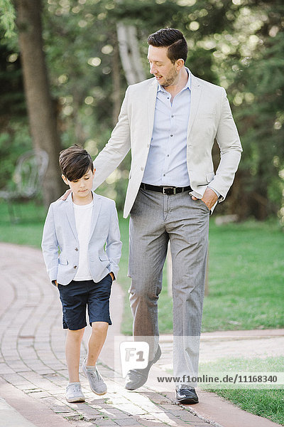 Father and son walking along a path in a garden.