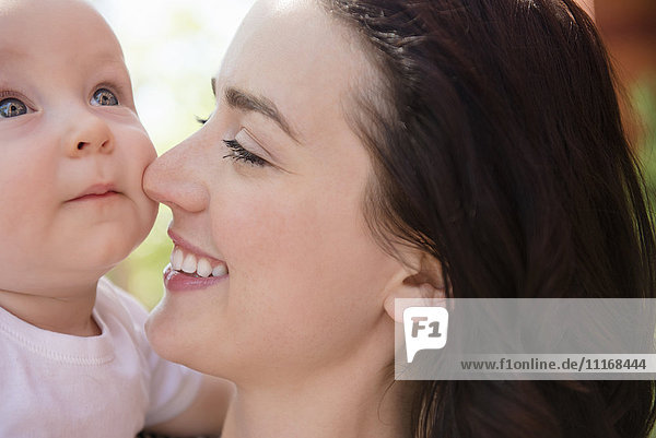 Kaukasische Mutter reibt Nase an Wange von Babysohn