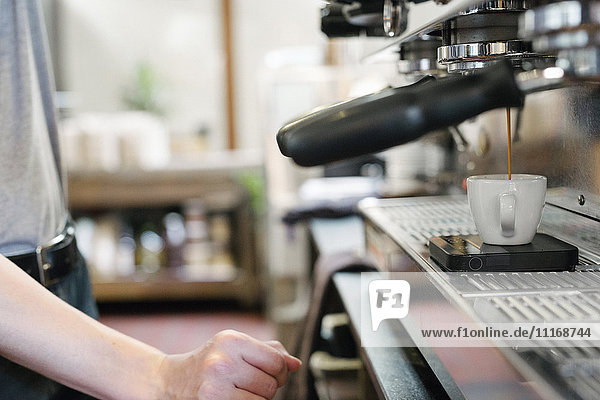 Mann steht vor einer Espressomaschine  frischer Espresso läuft in eine Tasse.