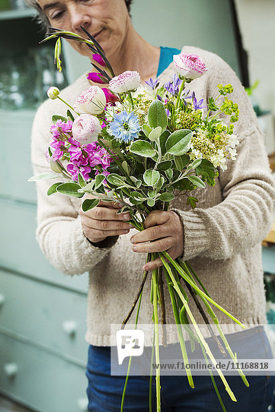 A florist creating a hand tied bunch of fresh flowers.