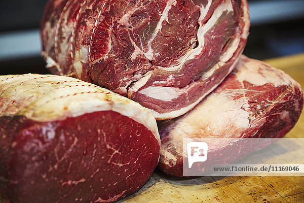 Close up of various large cuts of beef in a butcher's shop.