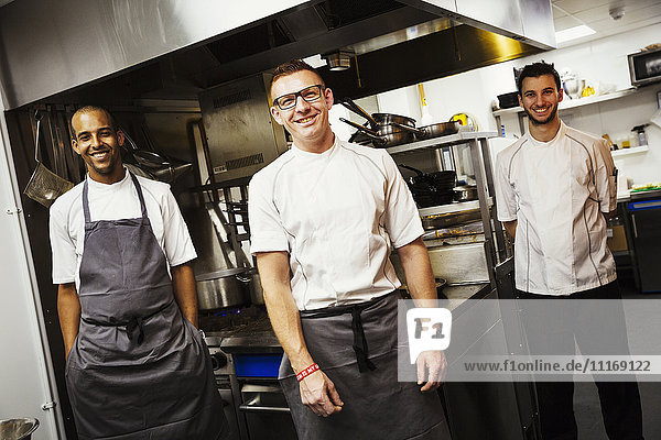 Portrait of three chefs standing in a restaurant kitchen.