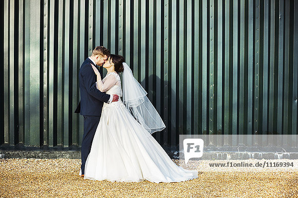 Eine Braut und ein Bräutigam an ihrem Hochzeitstag  die sich gegenseitig küssen.