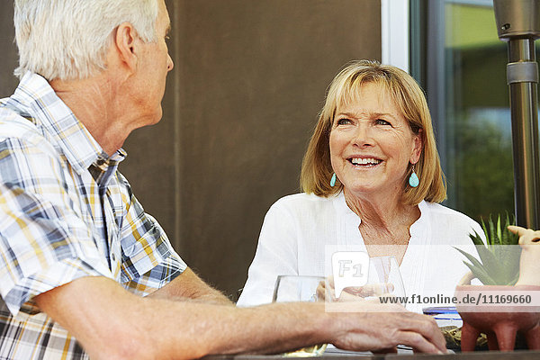 Lächelnde ältere Frau und Mann sitzen im Freien.