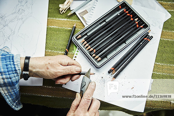 Eine Person  die eine scharfe Klinge  ein Cuttermesser  zum Anspitzen von Bleistiften verwendet. Skizzen auf Papier.