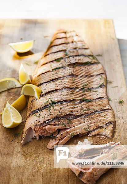 Lachs auf Schneidebrett mit Zitronenspalten