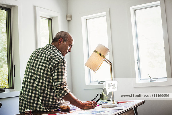 Ein Mann zu Hause mit einem Laptop auf einem Schreibtisch.