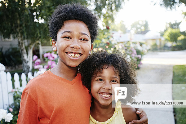 Lächelnde Mixed Race Bruder und Schwester umarmen im Freien