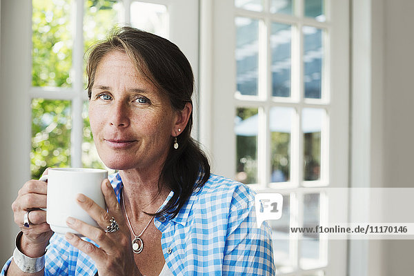 A woman drinking a mug of tea or coffee.