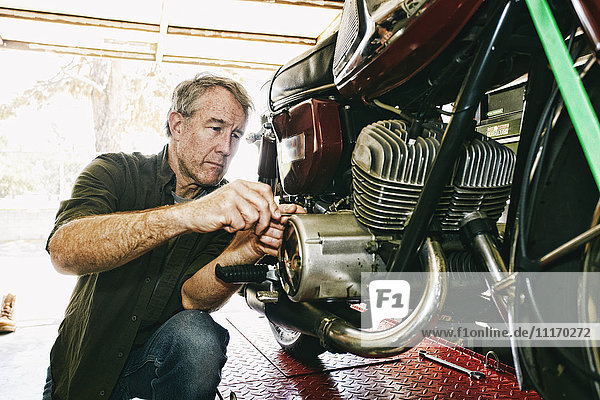 Kaukasischer Mann repariert Motorrad in Garage