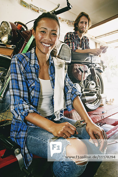 Lächelnder Mann und Frau reparieren Motorrad in der Garage