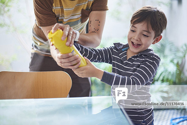 Hispanic boy helping father spray cleaner on table