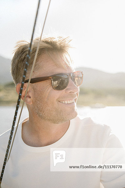 Portrait of a blond man with sunglasses on a sail boat.