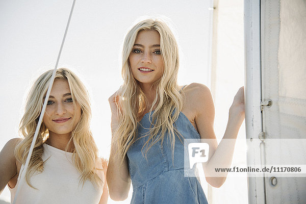 Portrait of two blond sisters on a sail boat.