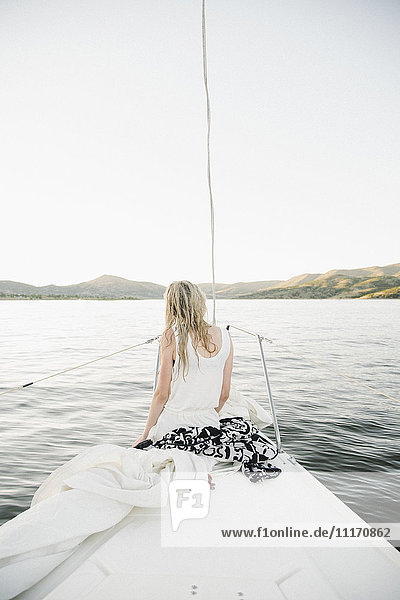 Blond teenage girl sitting on sail boat.
