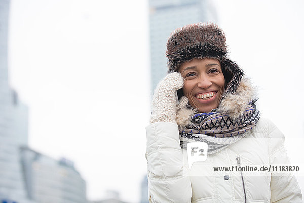 Cheerful woman in winter wear using cell phone outdoors