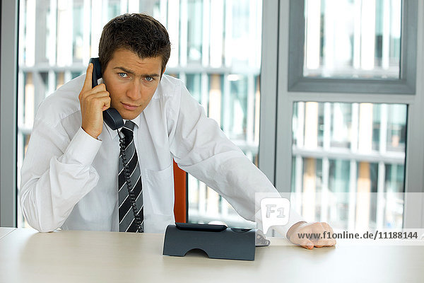 portrait of young confident caucasian businessman talking on phone