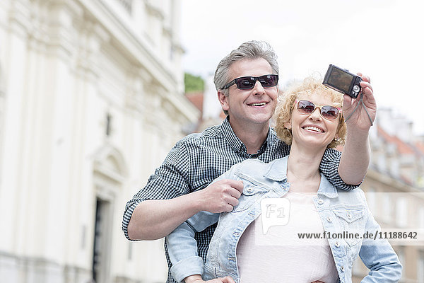 Happy middle-aged couple in sunglasses taking self portrait outdoors