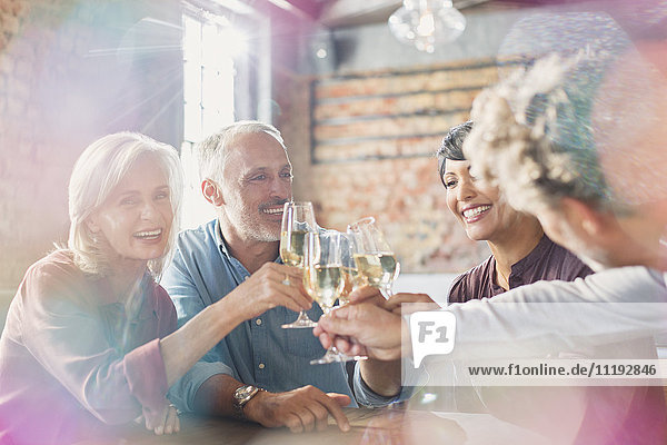 Friends toasting white wine glasses at restaurant table