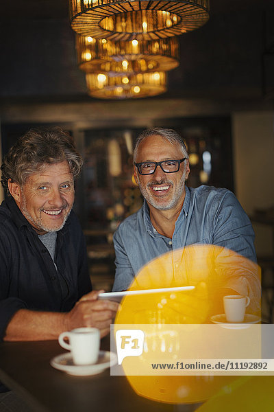 Portrait smiling men using digital tablet and drinking coffee at restaurant table