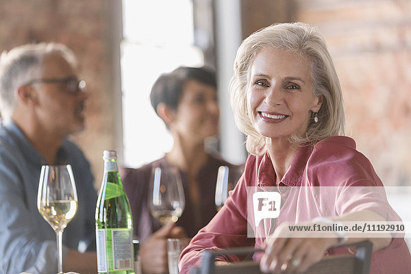 Porträt einer lächelnden älteren Frau  die mit Freunden im Restaurant speist