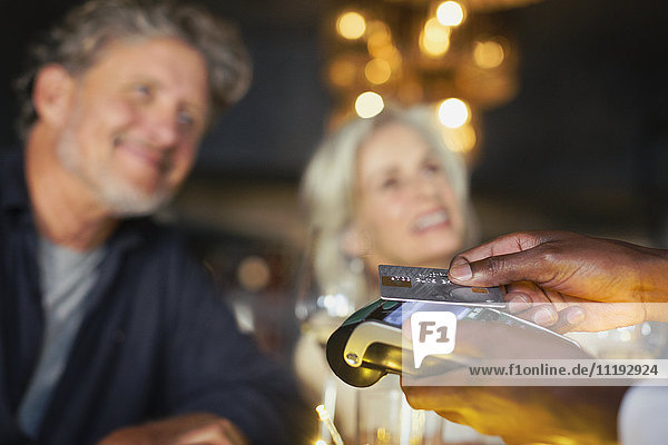 Close up couple paying waiter with credit card reader