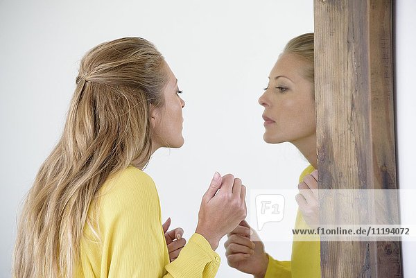 Schöne Frau beim Schminken im Spiegel