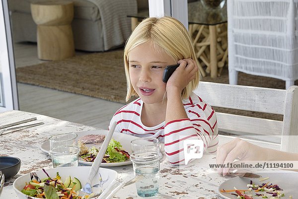 Kleines Mädchen  das beim Essen am Handy spricht