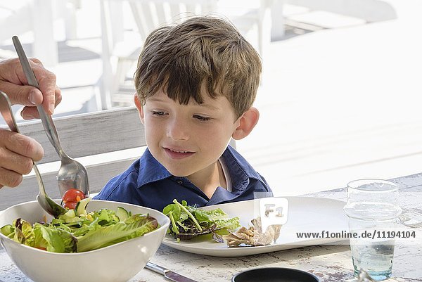 Parent serving food to son on table