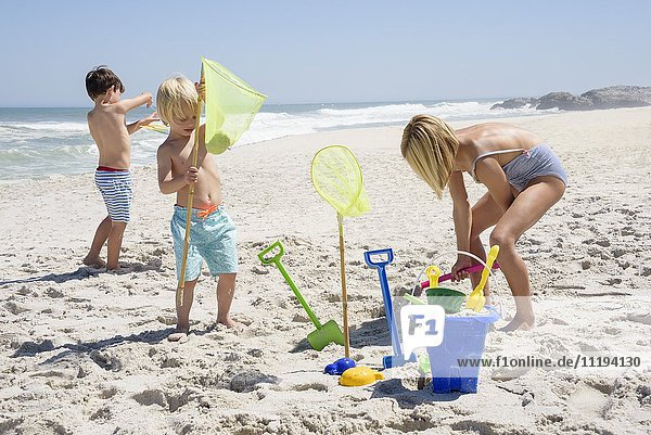 Drei Kinder spielen am Strand