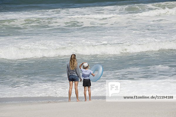 Rückansicht einer am Strand stehenden Frau mit ihrer Tochter