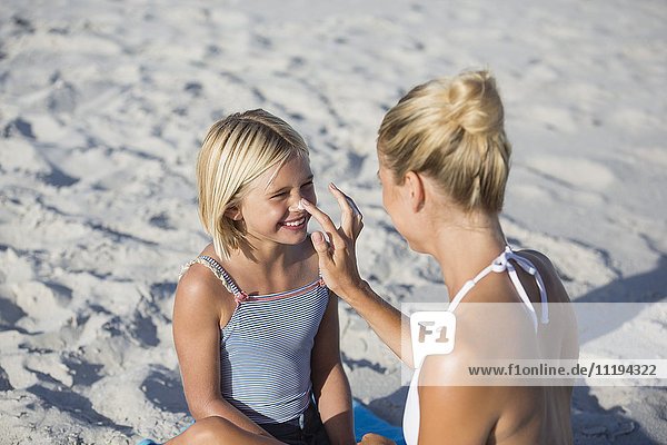 Frau mit Sonnenschutz auf der Nase ihrer Tochter
