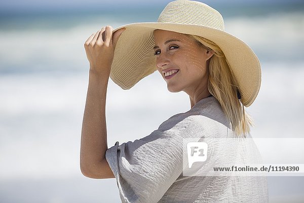 Porträt einer schönen jungen Frau mit Sonnenhut am Strand