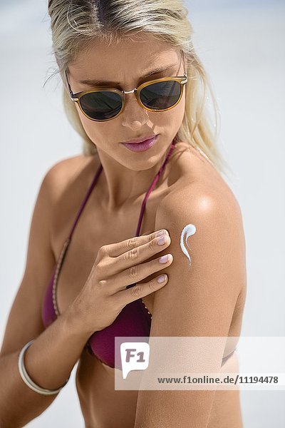 Profil einer Frau  die Sonnencreme auf ihren Körper aufträgt