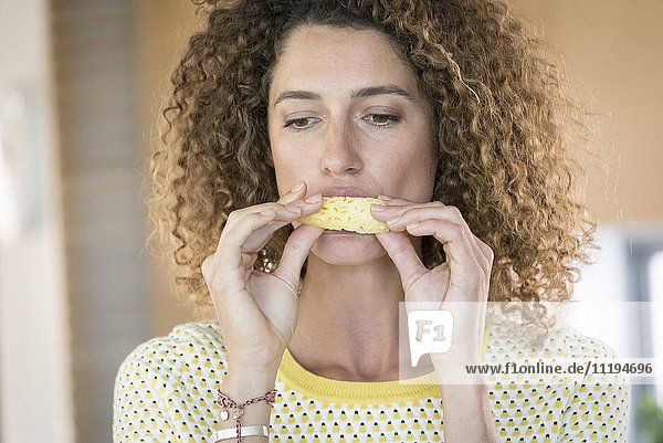 Young woman eating a slice of pineapple