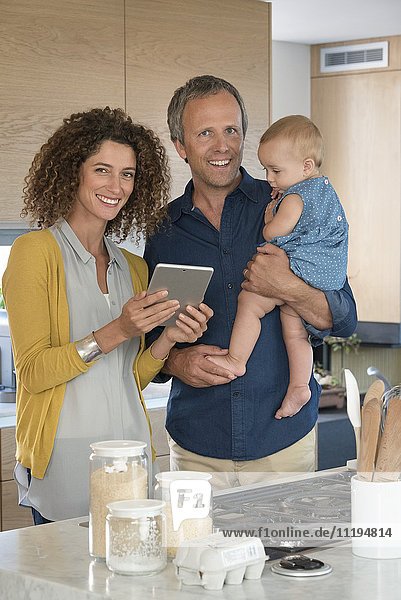 Couple using digital tablet with their daughter in the kitchen