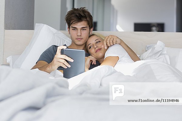 Junges Paar schaut sich Film auf digitalem Tablett an