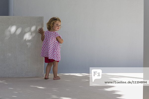 Rear view of a baby girl standing against a wall