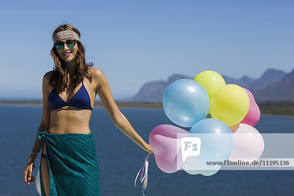 Fröhliche junge schöne Frau mit Luftballons