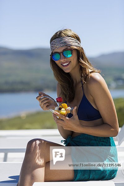 Fröhliche junge Frau mit einer Schale Obstsalat