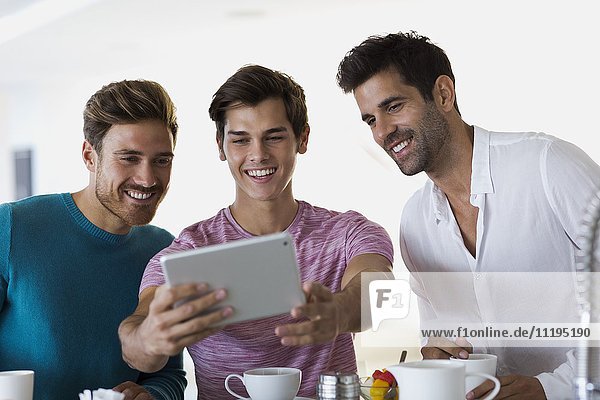 Nahaufnahme von drei glücklichen jungen Männern  die Selfie mit einem digitalen Tablett nehmen.