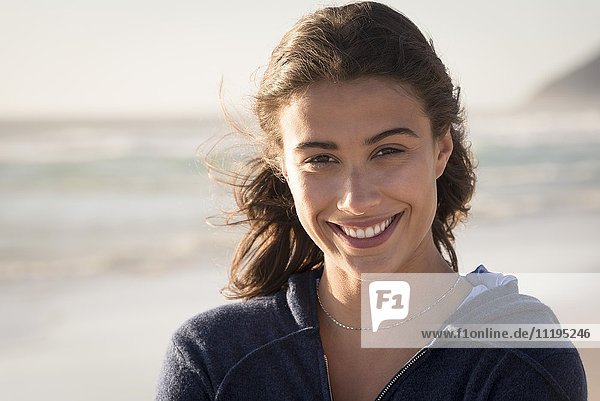 Porträt einer fröhlich schönen jungen Frau am Strand