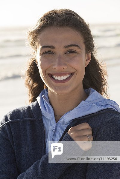 Hübsche junge Frau  die am Strand lächelt.