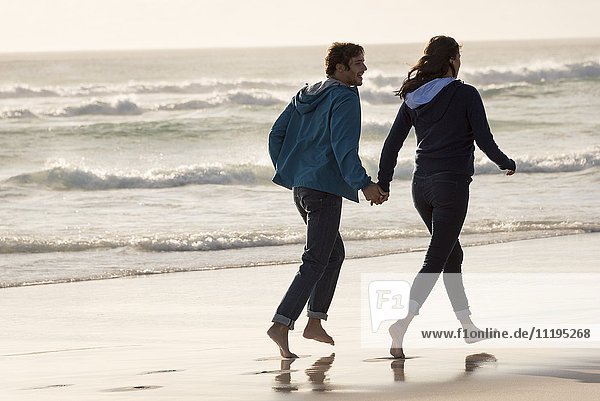 Happy young couple running on beach
