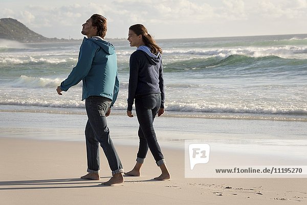 Ein glückliches junges Paar geht am Strand spazieren.