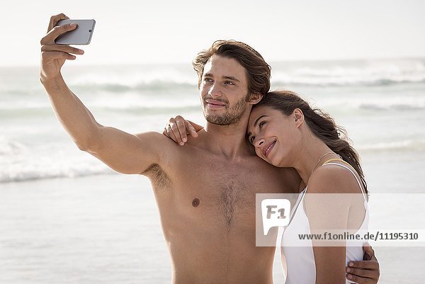 Ein glückliches junges Paar  das sich mit einem Smartphone selbstständig macht.
